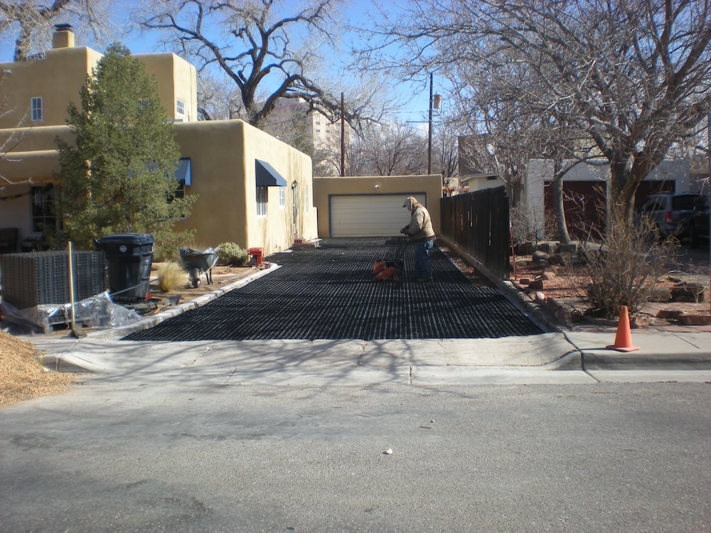 Person using a hand tool to install Ecoraster permeable paving on a residential driveway